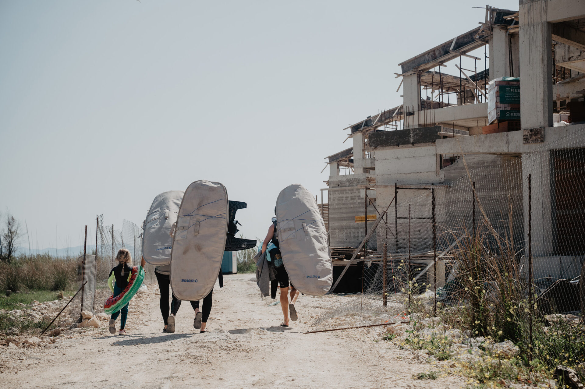 Vass beach House Team walking through building site to go wing-foiling
